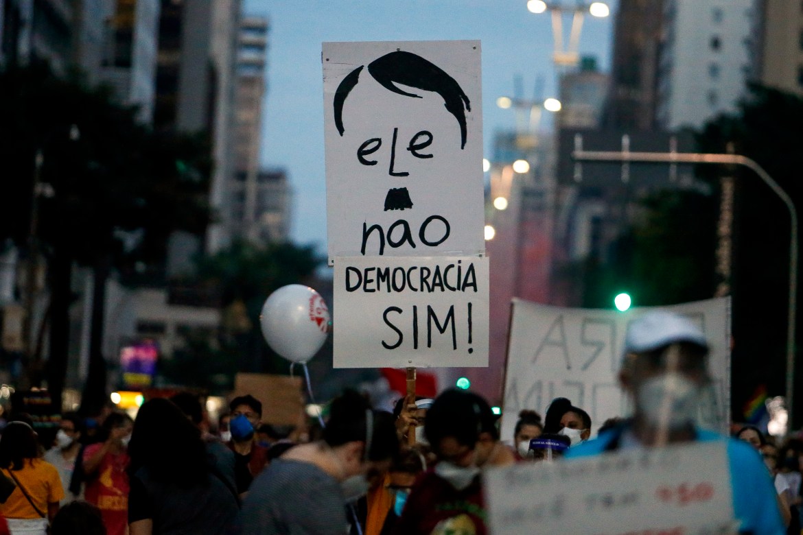 A protester holds a placard that says in Portuguese under a picture of the president saying "He is no .. democracy yes" during a protest on Paulista Avenue in Sao Paulo (Getty Images)
