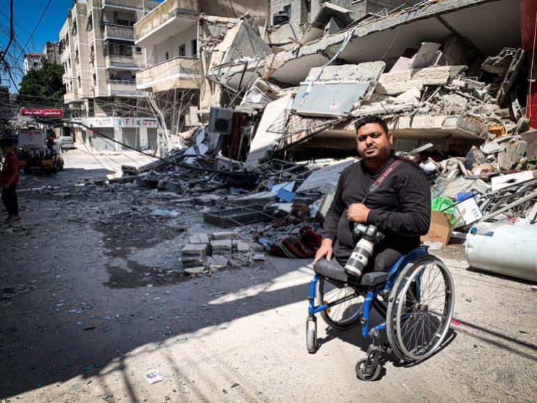 المصور الصحفي مؤمن قريقع أمام البناية التي كانت تضمن مؤسسة آيديا للانتاج الإعلامي وقد دمرها القصف الاسرائيلي