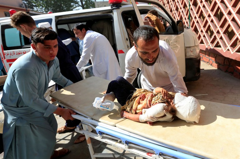 A man carries an injured child at a hospital after a truck bomb blast in Jalalabad