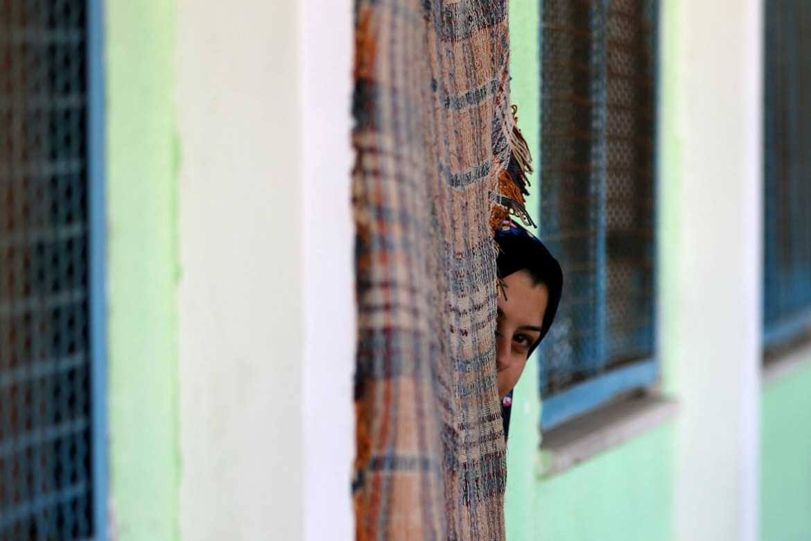 A Palestinian woman hides from the cameraman in a classroom in a school of the United Nations Relief and Works Agency (UNRWA) in Gaza, who was displaced to her after one of the continuous air strikes of the Israeli occupation army on the Strip (Reuters)