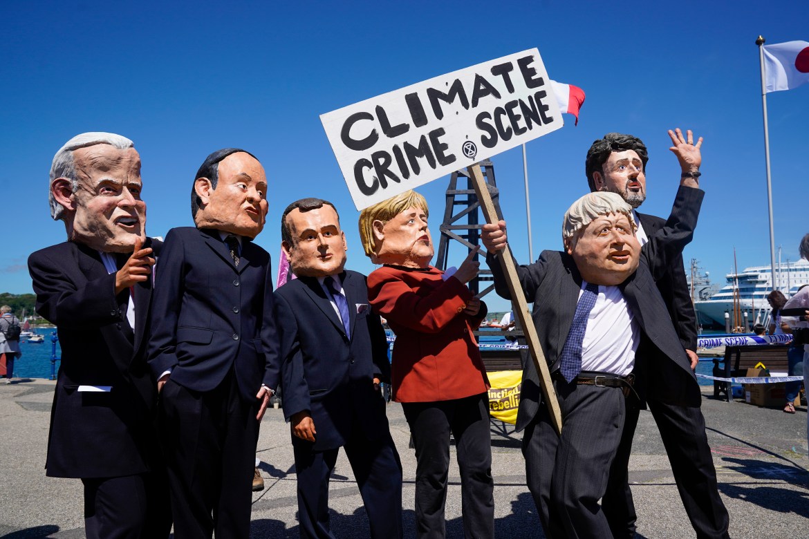 محتجون يرتدون أقنعة قادة دول مجموعة  السبع، بينما حمل صاحب قناع جونسون لافتة كتب عليها "مسرح جريمة المناخ" (الفرنسية)