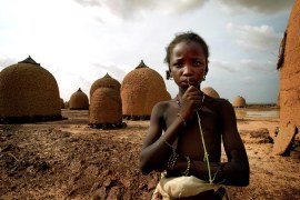 Girl stands in front of empty granaries at village of Tangaba, in northwestern Niger.
