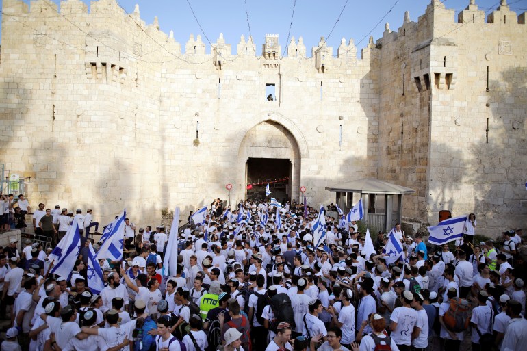 Jewish youth wave Israeli flags as they participate in a march marking "Jerusalem Day", near Damascus Gate in Jerusalem's Old City