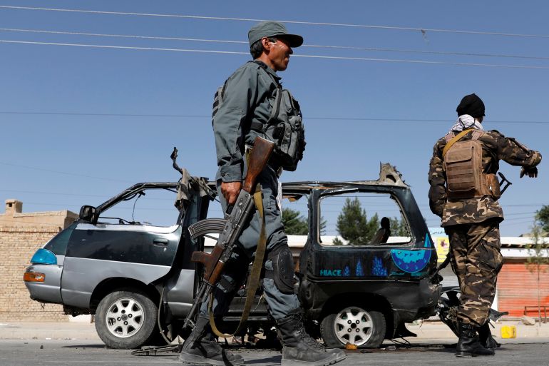 Afghan police officer inspects a damaged van after a blast in Kabul
