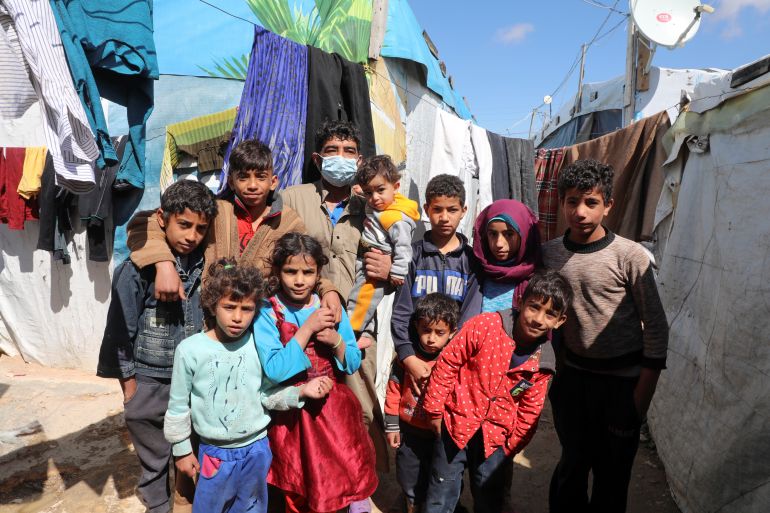 Syrian refugee Abd al-Razzak Dasher stands with his children at an informal tented settlement in the Bekaa valley