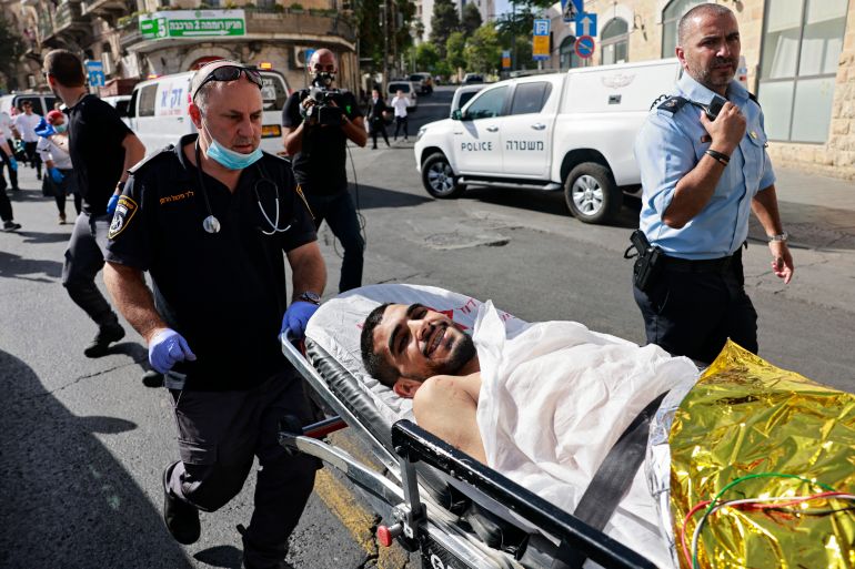 Israeli medics stretch off a wounded Palestinian man, who stabbed two Israelis, in Jerusalem on September 13, 2021. A police spokesman told AFP the assailant was a Palestinian man from the West Bank city Hebron. There was no immediate indication about the condition of the assailant, who was seen smiling by an AFP photographer as he was taken away for medical treatment. Menahem KAHANA / AFP