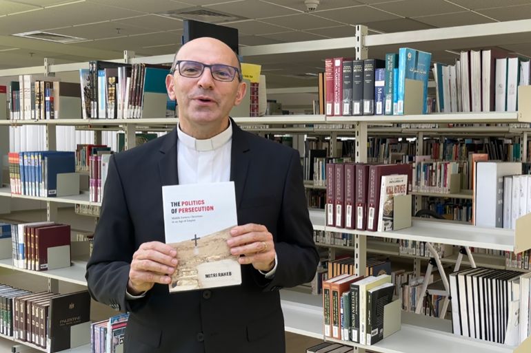 د. متري الراهب يحمل كتابه، وصورة لغلاف الكتاب الذي ألفه باللغة الانجليزية