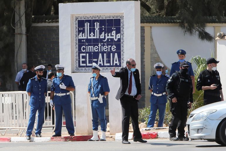 Police members stand outside El Alia cemetery, in Algiers