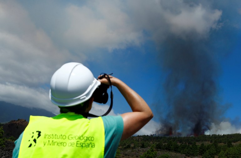 A member of Spanish Geological Mining Institute observes smoke rising following the eruption of a volcano in Spain