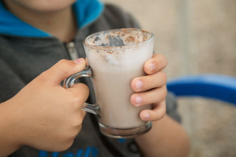 a large Cup of cocoa with milk in the hands of a child; Shutterstock ID 1774220285; purchase_order: aljazeera net; job: ; client: ; other: