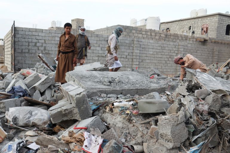 People browse through the rubble of a house destroyed by Houthi missile attack in Marib