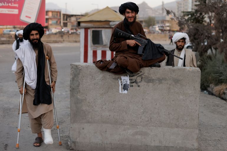 Taliban fighter Mira Jan Himmat, 30, and Rafiullah, 26, from Helmand province smile as they stand guard in a checkpoint in Kabul