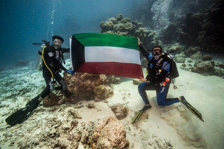 الموسوي يحمل علم الكويت تحت الماء المصدر: الصحافة الكويتية