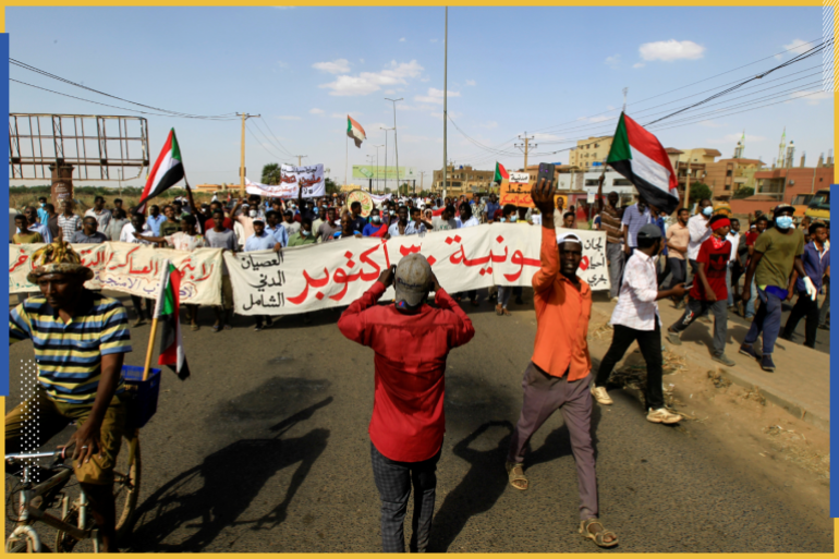 Protesters carry a banner and national flags as they march against the Sudanese military's recent seizure of power and ousting of the civilian government, in the streets of the capital Khartoum, Sudan October 30, 2021. REUTERS/Mohamed Nureldin