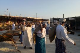 عمال ينشدون الأغاني القديمة المرتبطة بالبحر والسفن على شاطىء كتارا (الجزيرة)