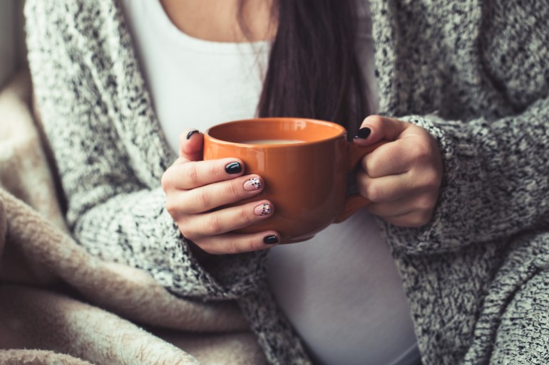 Woman with beautiful manicure and orange cup of cocoa بدائل للقهوة تستمتعين بها خلال الحمل