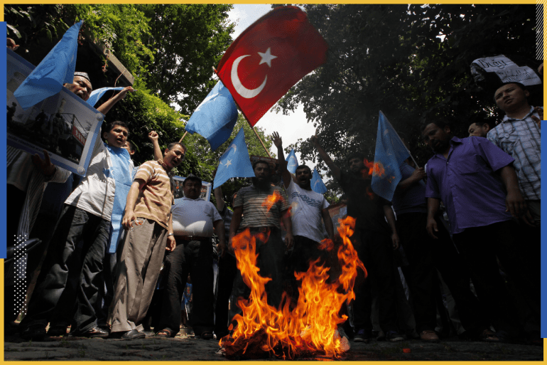 متظاهرون من طائفة الأويغور ، وهم يلوحون بالأعلام التركية والأزرق من تركستان الشرقية ، النار في العلم الصيني خلال احتجاج ضد الصين بالقرب من القنصلية الصينية في اسطنبول
