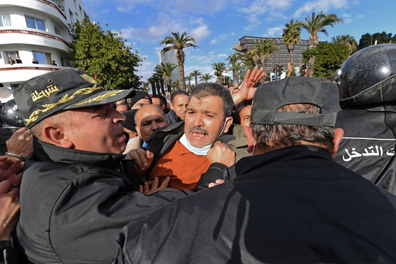 A Tunisian demonstrators clash with police during protests against President Kais Saied, on the 11th anniversary of the Tunisian revolution in the capital Tunis on January 14, 2022. - Tunisian police used teargas today against hundreds of demonstrators who had defied a ban on gatherings to protest against President Kais Saied's July power grab. As the country marks 11 years since the fall of late dictator Zine El Abidine Ben Ali, hundreds of Saied's opponents staged rallies against his July 2021 power grab. (Photo by FETHI BELAID / AFP)