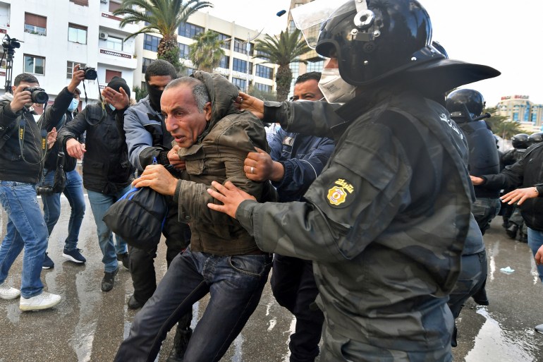 A Tunisian man is arrested following clashes with police during protests against President Kais Saied, on the 11th anniversary of the Tunisian revolution in the capital Tunis on January 14, 2022. - Tunisian police used teargas today against hundreds of demonstrators who had defied a ban on gatherings to protest against President Kais Saied's July power grab. As the country marks 11 years since the fall of late dictator Zine El Abidine Ben Ali, hundreds of Saied's opponents staged rallies against his July 2021 power grab. (Photo by FETHI BELAID / AFP)
