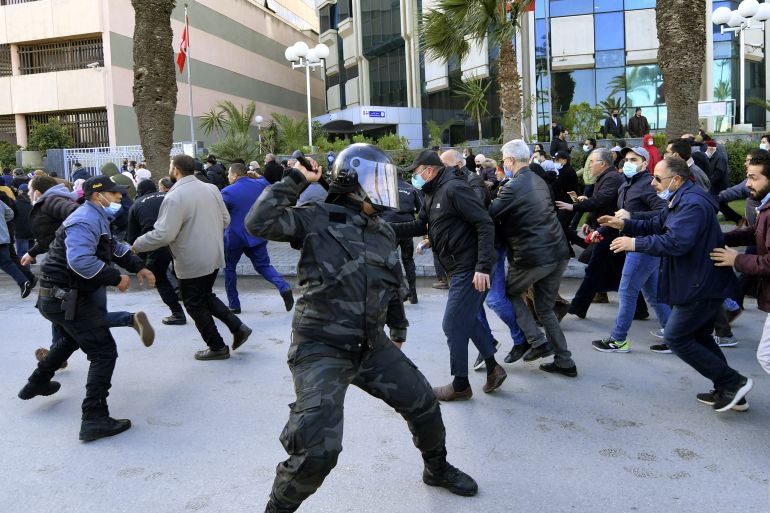 Tunisian demonstrators run for cover during clashes with police as they protest against President Kais Saied, on the 11th anniversary of the Tunisian revolution in the capital Tunis on January 14, 2022. - Tunisian police used teargas today against hundreds of demonstrators who had defied a ban on gatherings to protest against President Kais Saied's July power grab. As the country marks 11 years since the fall of late dictator Zine El Abidine Ben Ali, hundreds of Saied's opponents staged rallies against his July 2021 power grab. (Photo by FETHI BELAID / AFP)
