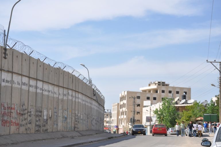 جدار الفصل العنصري بمساره بضاحية الرام حيث فصلها عن القدس المحتلة.