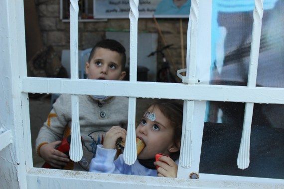 8-الطفلان جمال وسلمى عطية يتحدثان مع المارة من خلف البوابة الحديدية المؤدية لمنزلهما(الجزيرة نت)