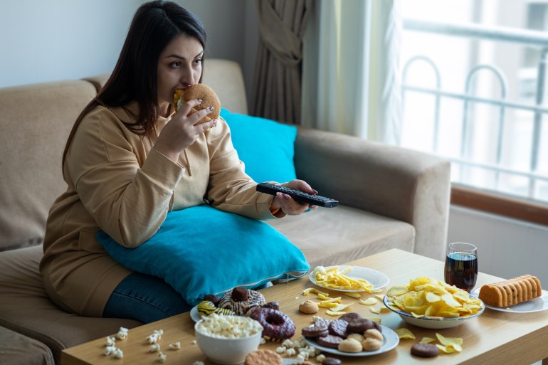 - EATING FOOD - WINTER - Overweight woman sitting on sofa