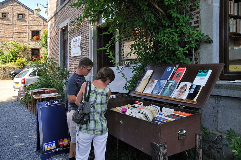 Tourists choosing books from bookshop in the book town Redu, Belgian Ardennes, Luxembourg, Belgium. (Photo by: Arterra/Universal Images Group via Getty Images)
