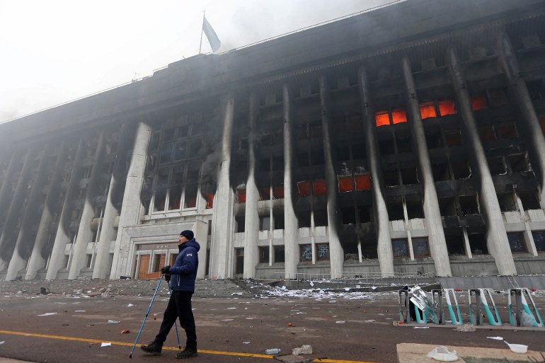 A man stands in front of the mayor's office building which was torched during protests in Almaty