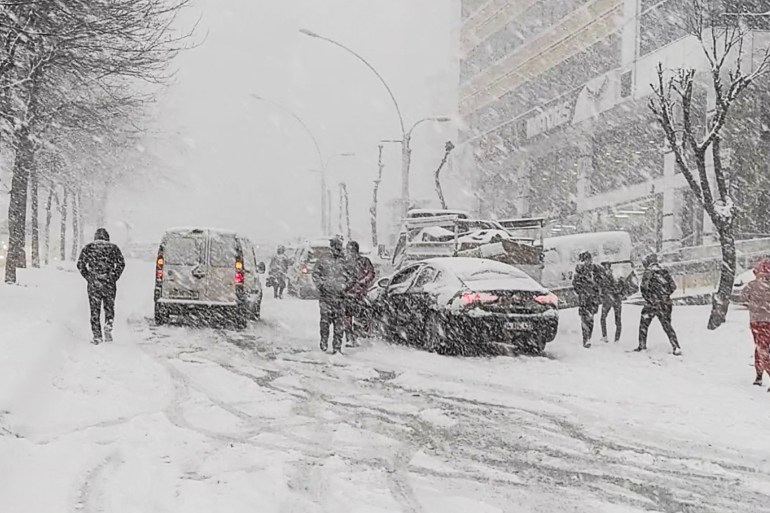 People walk by stopped cars amid heavy snowfall in Istanbul, Turkey, January 24, 2022 in this still image obtained from a social media video taken on January 24, 2022. Okan Tanis/via REUTERS THIS IMAGE HAS BEEN SUPPLIED BY A THIRD PARTY. MANDATORY CREDIT. NO RESALES. NO ARCHIVES.