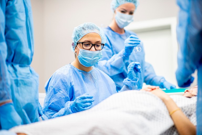 Team of doctors and nurses wear masks and gloves and prepare for surgery.