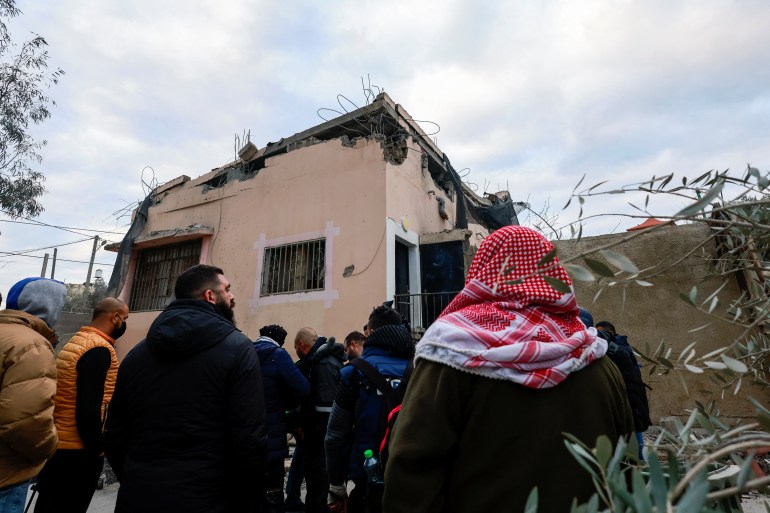 People gather next to a Palestinian house after it was blown up by Israeli forces, near Jenin