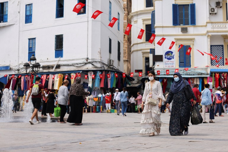 People wearing protective face masks walk past shops, amid the coronavirus disease (COVID-19) outbreak, in the Old City of Tunis