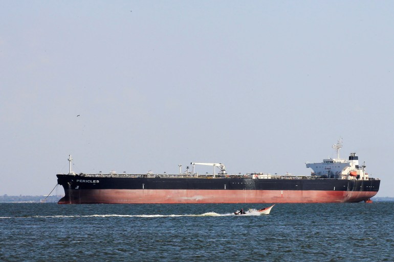 A fisherman's boat sails near the oil tanker Pericles while it is moored on Lake Maracaibo in Maracaibo