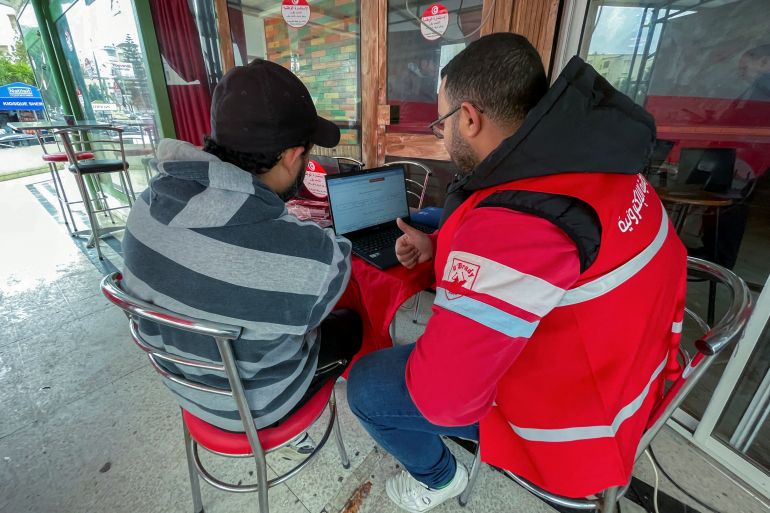 A volunteer explains to a citizen about an online multiple-choice questionnaire in Tunis