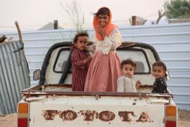 Children ride on the back of a truck at a camp for internally displaced people (IDPs) in Marib