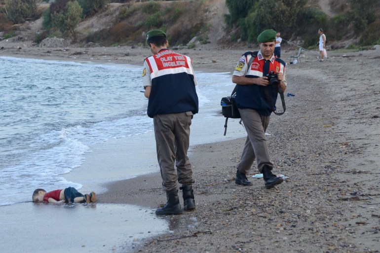 Turkish officials in the coastal town of Bodrum stand near the body of a refugee child who drowned during a failed attempt to sail to the Greek island of Kos. (Dogan News Agency/EPA)