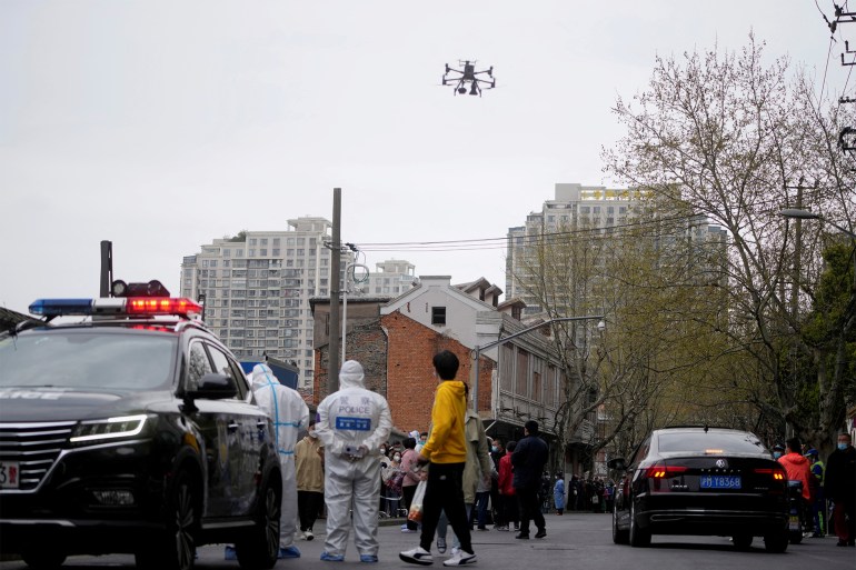A drone with a loudspeaker reminding residents to follow epidemic preventive measures flies over people lining up to buy food, following the coronavirus disease (COVID-19) outbreak in Shanghai, China March 30, 2022. REUTERS/Aly Song REFILE - CORRECTING YEAR