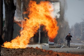 A man walks past a burning gas pipeline that was hit during shelling from Russian positions in a neighbourhood in northern Kharkiv as Russia's attack on Ukraine continues