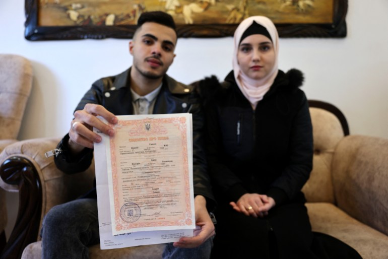 Ukrainian Viktoria Saidam (R), accompanied by her Palestinian husband Ibrahim Saidam, show their marriage contract at their family home in the refugee camp of Bureij in the central Gaza Strip on March 22, 2022. - After Russia invaded Ukraine, Viktoria Saidam knew she needed to find a "safer place" than Kyiv and ultimately chose her husband's homeland -- a Palestinian territory not typically associated with security: Gaza. Saidam, 21, was born Viktoria Breij in Vinnytsia, a town some 200 kilometres (125 miles) southwest of Ukraine's capital. (Photo by SAID KHATIB / AFP)