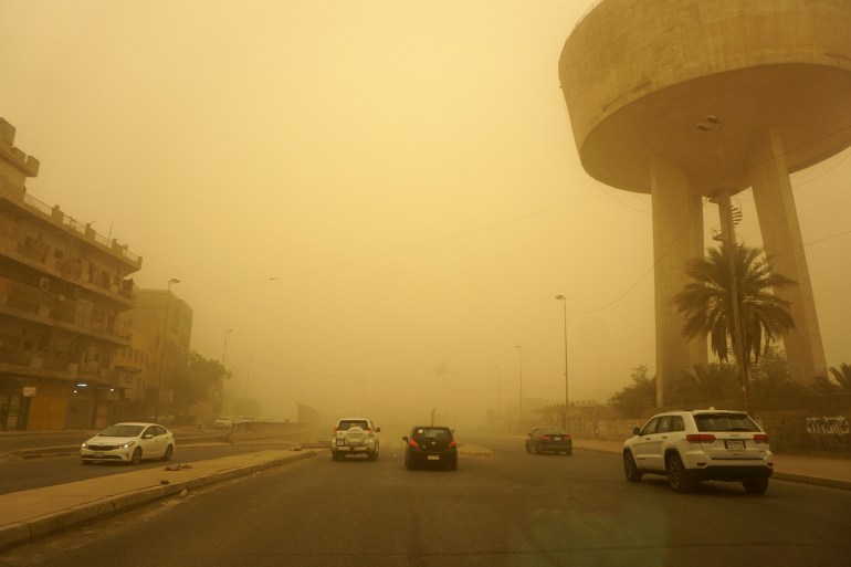 Vehicles drive down a road in Iraq's capital Baghdad as thick dust blankets the city, on May 23, 2022. - Iraq closed airports and public buildings as a dust storm -- the ninth since mid-April -- hit the country, authorities said. (Photo by Sabah ARAR / AFP)