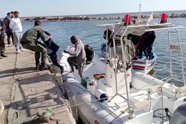 Tunisian national coast guards help migrants to get off a rescue boat in Jbeniana