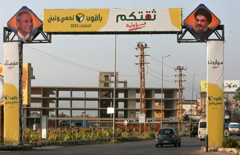 Vehicles pass near an electoral campaign sign in Abbasiyeh