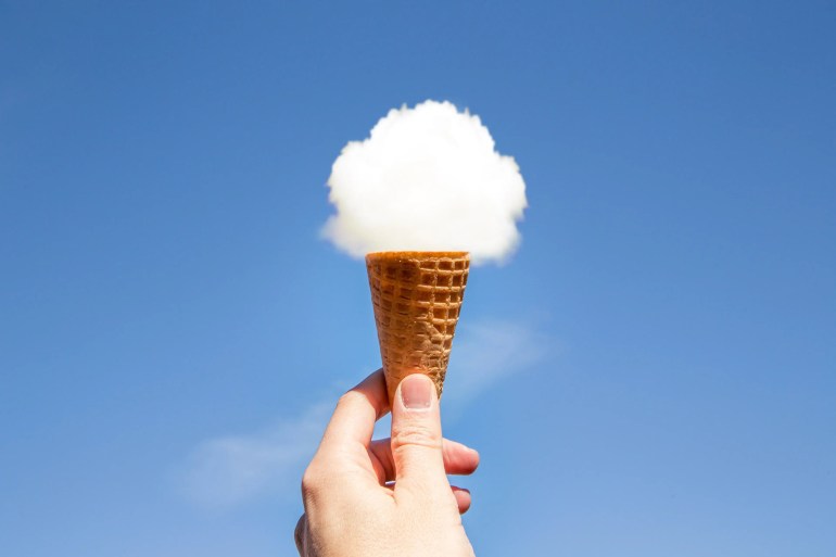 Creative picture of guy holding ice cream cone in the sky with round cloud on the top of cookie cornet.