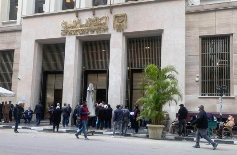 epa09842261 Egyptians wait outside a branch of the National Bank of Egypt, in Cairo, Egypt, 22 March 2022. The Egyptian pound fell by more than 17 percent against the US dollar since 21 March, while the Central Bank of Egypt increased rates by 100 basis points in an unexpected monetary policy meeting, citing global inflationary pressures due to the COVID-19 pandemic and the recent Russia-Ukraine conflict. EPA-EFE/KHALED ELFIQI