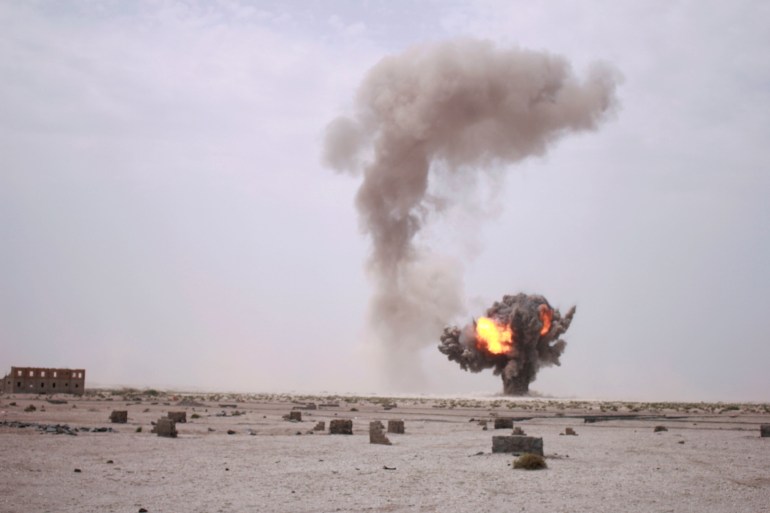 Smoke and fire billows during controlled explosions by Yemeni military demining unit to destroy unexploded bombs and mines collected from conflict areas near the southern port city of Aden, Yemen