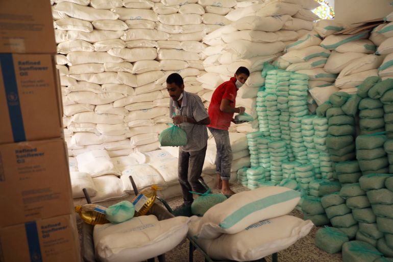 Workers prepare foodstuff for beneficiaries at a food distribution center supported by the World Food Program in Sanaa