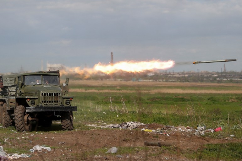 Service members of pro-Russian troops fire a BM-21 Grad multiple rocket launch system in Mariupol