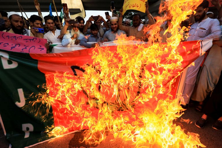 People burn a flag depicting Indian Bharatiya Janata Party (BJP), during a protest in Peshawar