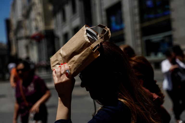 A woman covers her head with a bag during a hot day as Spain braces for a heatwave in Madrid